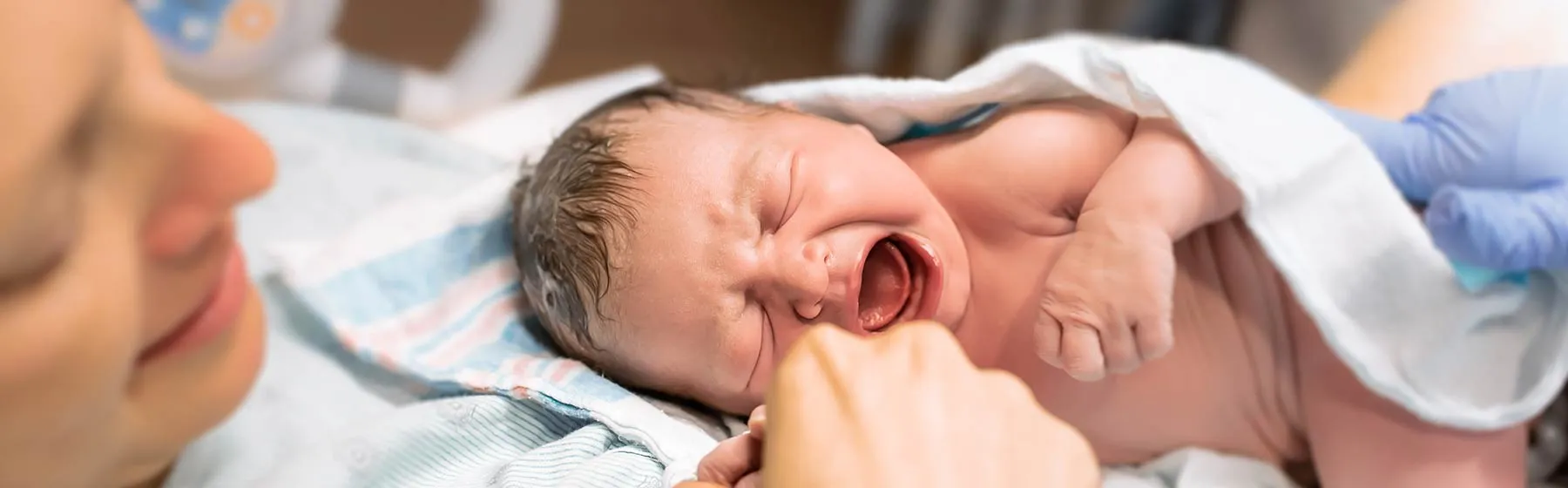 Bébé qui pleure dans les bras de sa mère