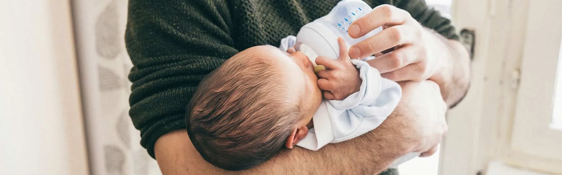 Bébé allongé dans les bras de son père