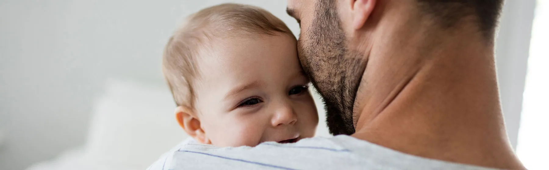 Bébé dans les bras de son père de dos