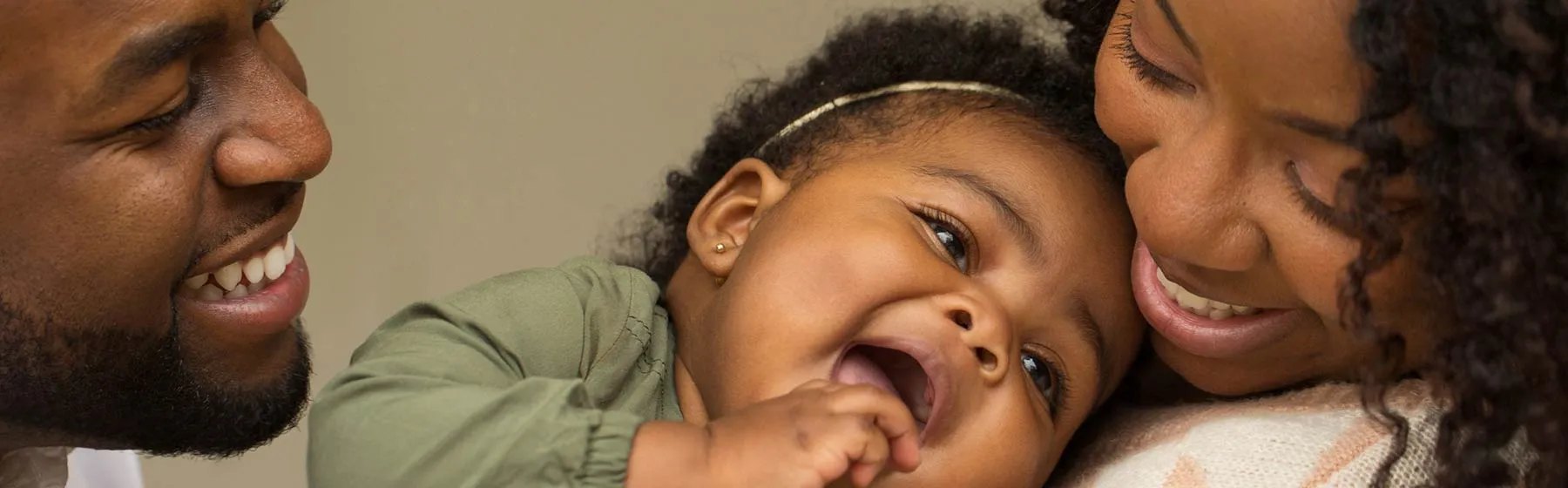 Bébé dans les bras de ses parents, souriants
