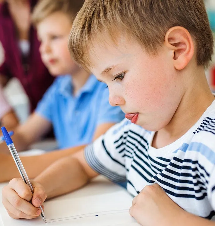 Enfant qui écrit avec un stylo bleu