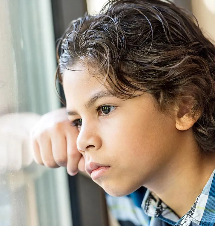 Enfant triste regardant par la fenêtre