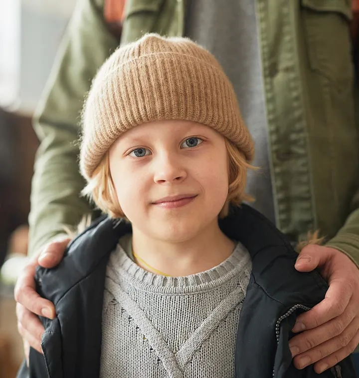 Enfant avec un bonnet tenu par les épaules par un adulte