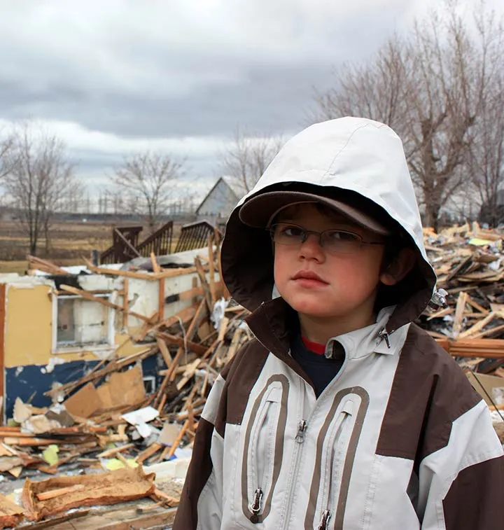 Enfant devant une maison détruite par un tremblement de terre