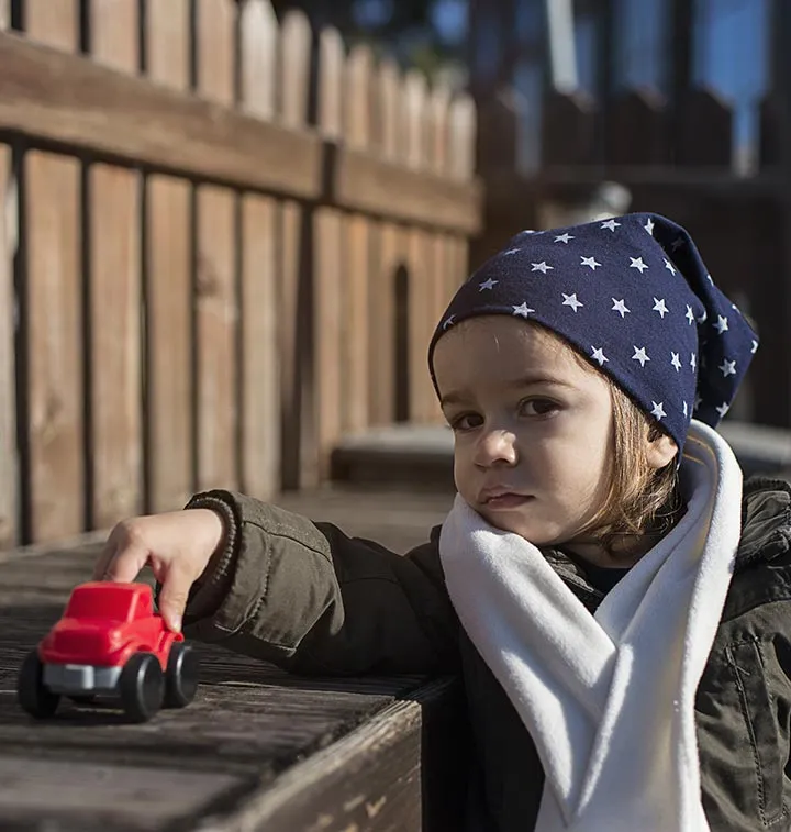 Petite fille triste qui joue avec une petite voiture rouge