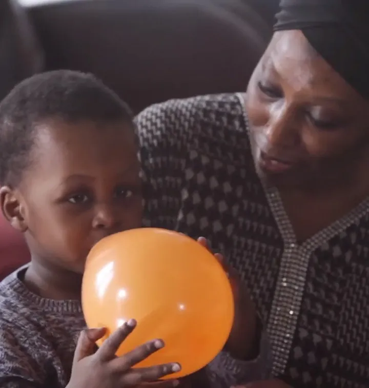 Maman avec son fils qui souffle dans un ballon orange