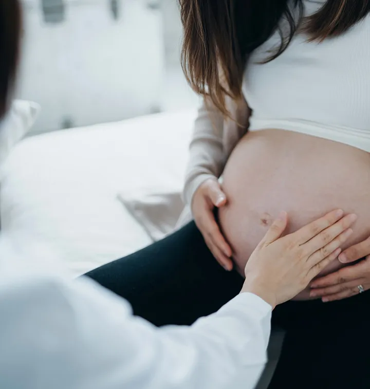 Sage-femme posant sa main sur le ventre d'une femme enceinte