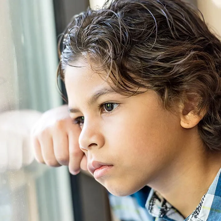 Enfant triste regardant par la fenêtre