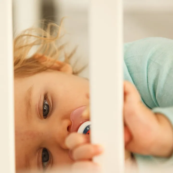Gros plan sur le visage d'un bébé dans son lit à barreaux