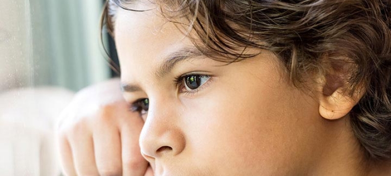 Enfant triste regardant par la fenêtre