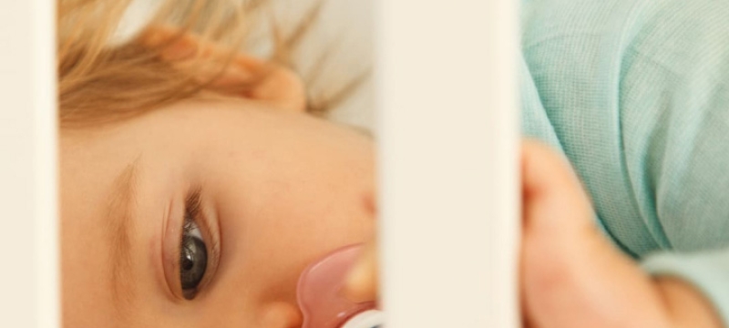 Gros plan sur le visage d'un bébé dans son lit à barreaux
